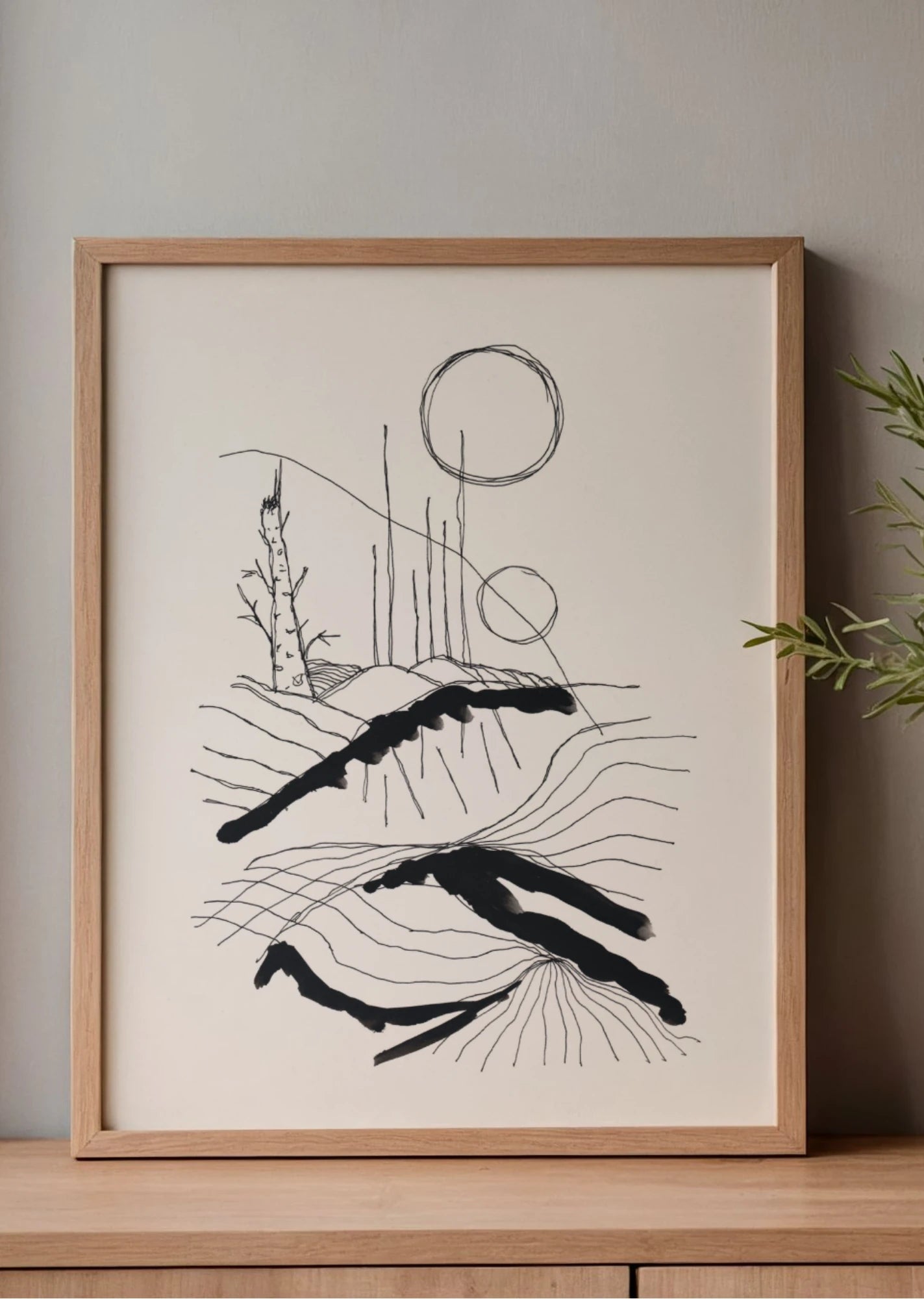 Minimalistisk svartvit poster i ekram på träbyrå med mjuka naturtoner och stilren interiör.