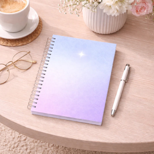 spiralblock i blå och lila toner/gradient med silver stjärna i minimalistisk design, som ligger på ett bord.