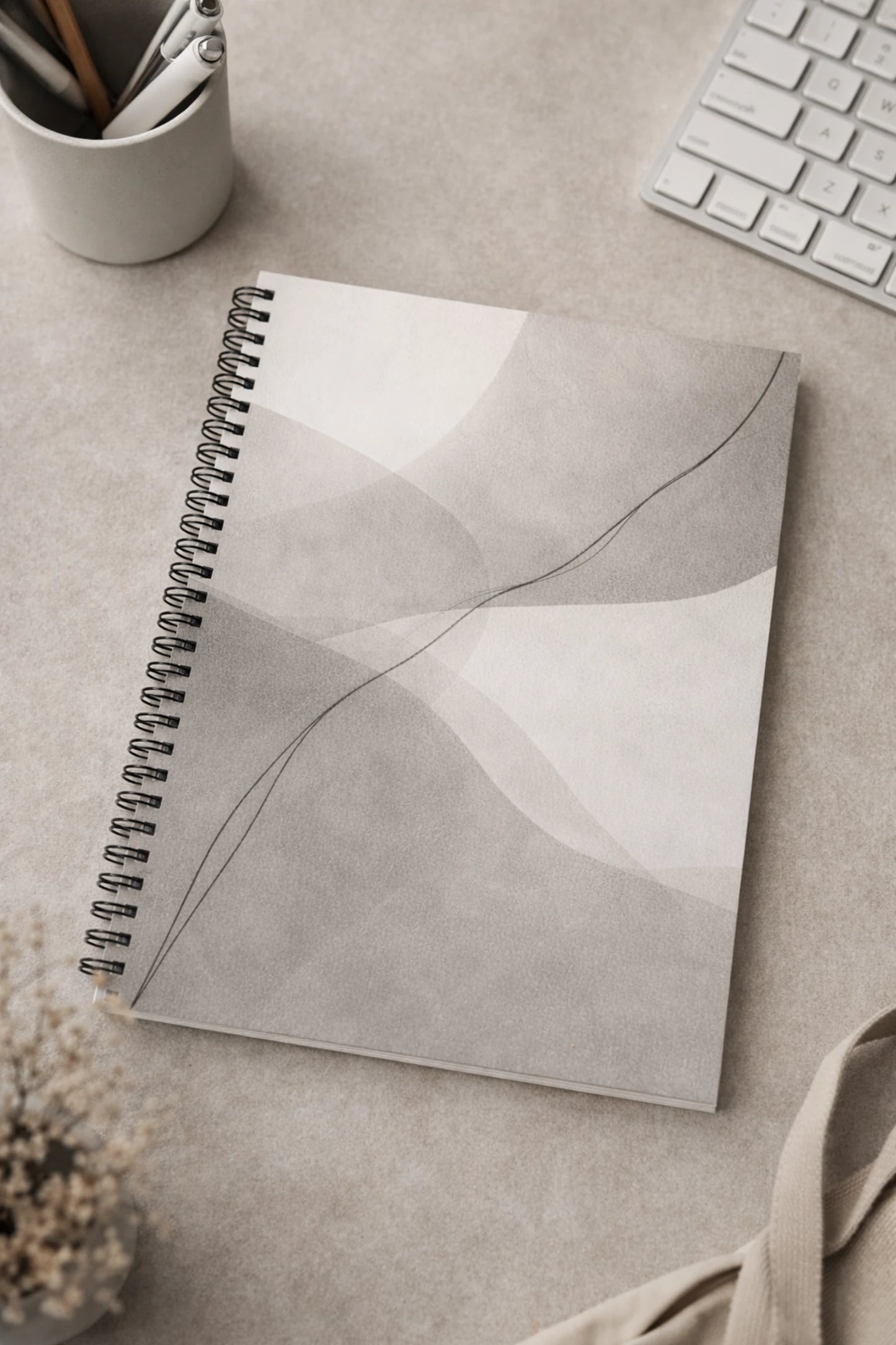 Minimalistiskt kollegieblock med abstrakt linjemotiv på stilrent skrivbord i mjuka beige och grå toner.