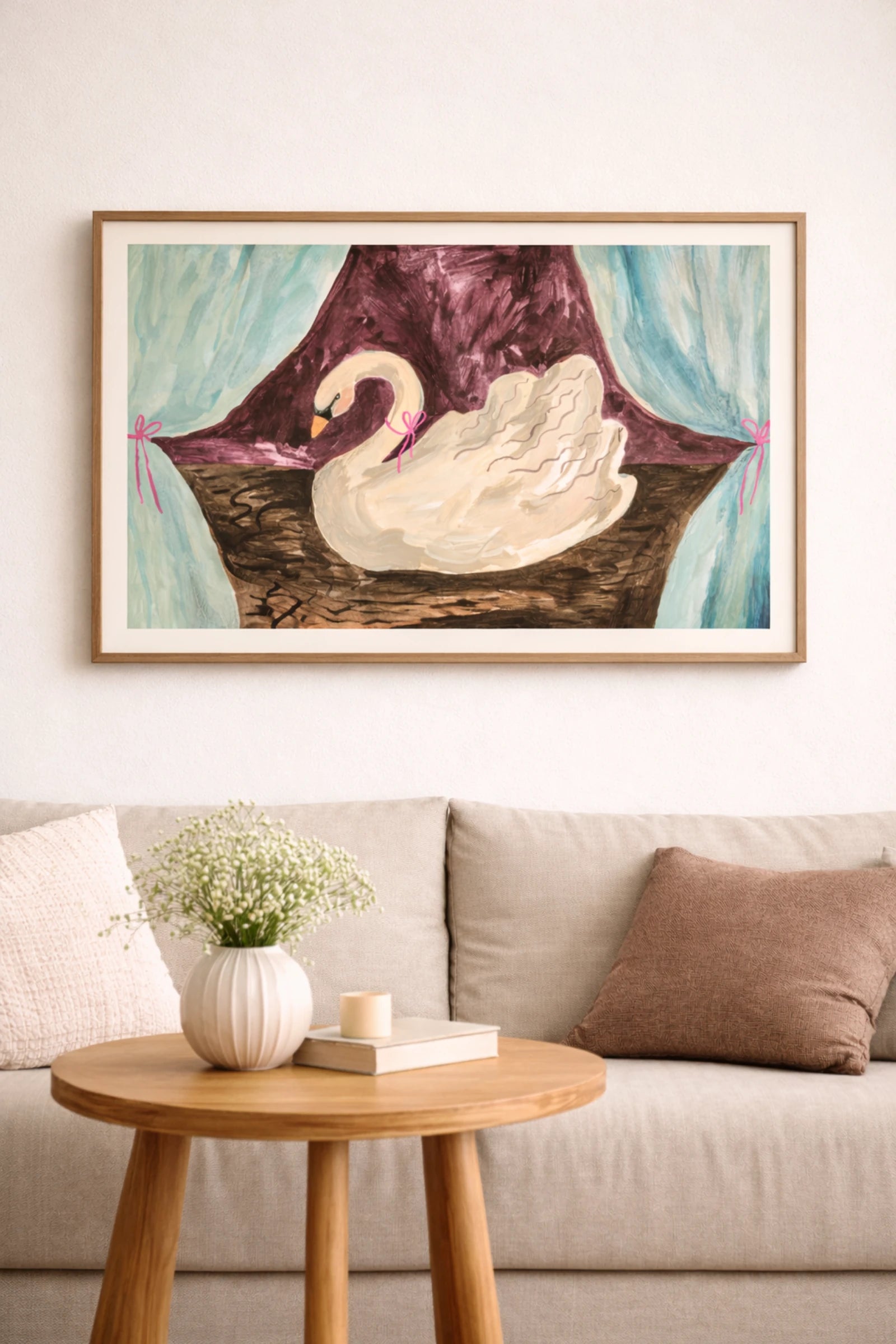 Färgglad svanposter i träram ovanför beige soffa i varm och hemtrevlig vardagsrumsmiljö.