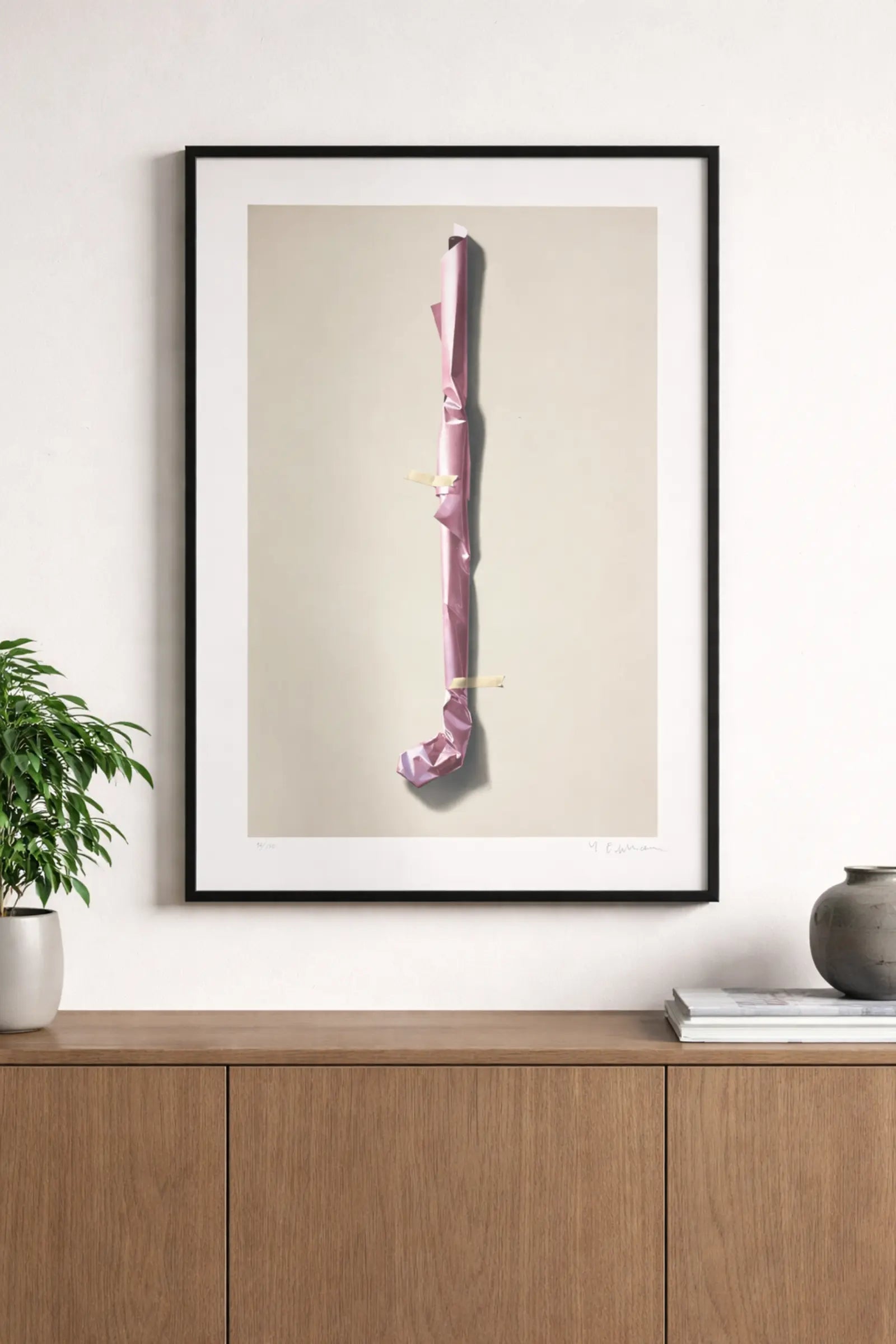 Minimalistisk poster med rosa abstrakt objekt i svart ram mot ljus modern interiör.