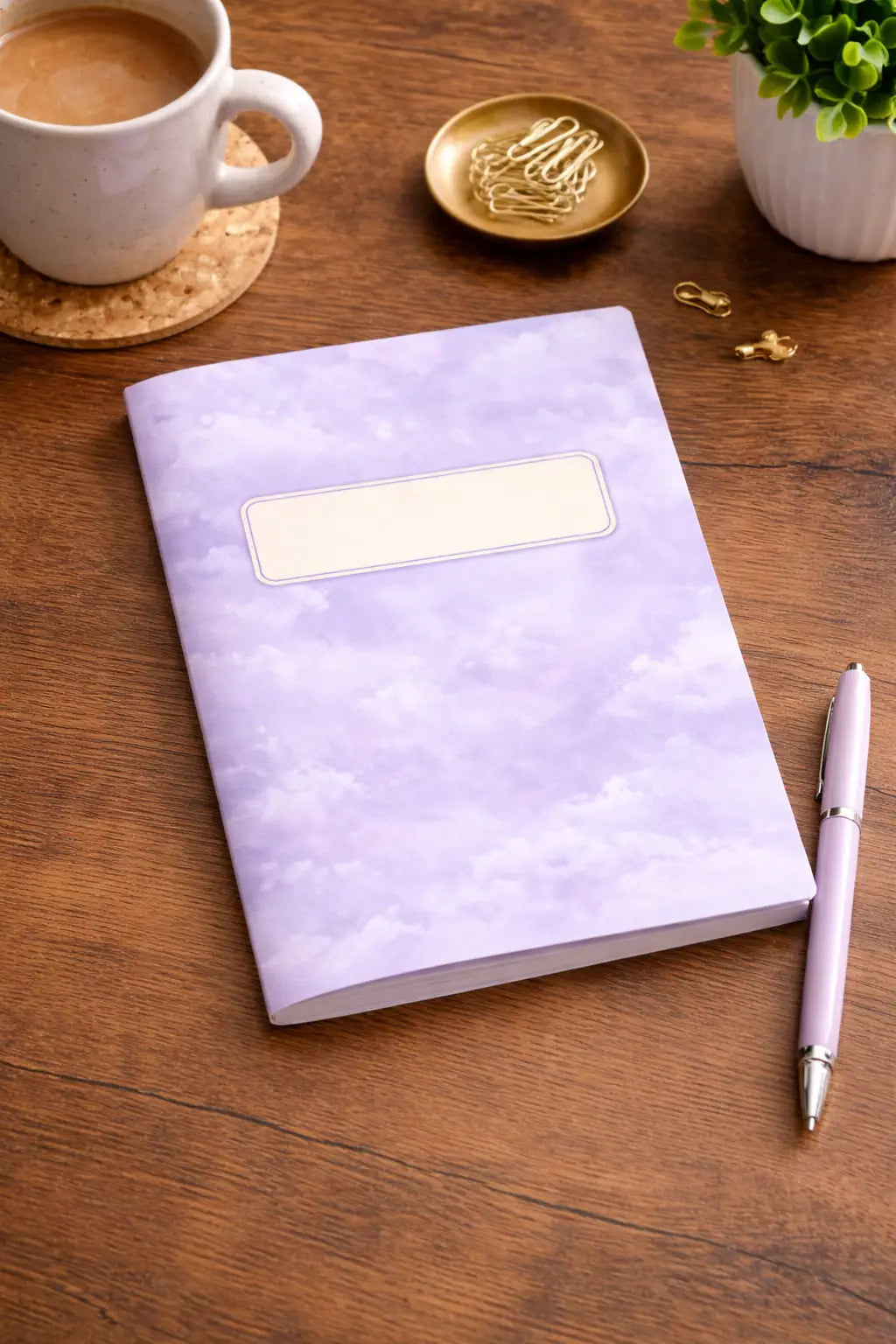Purple Sky Notebook anteckningsbok i ljus lila design med molnmönster som ligger på ett srivbord